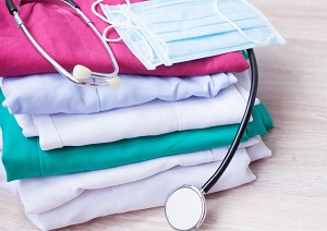 Pile of Folded Scrubs with a Stethoscope and Mask on Top