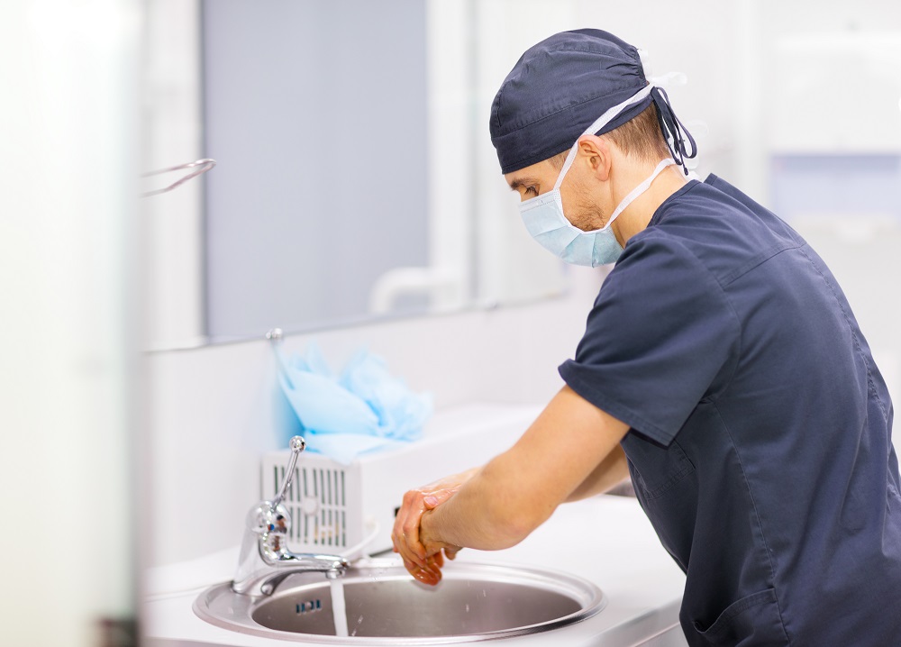 Doctor in scrubs washing hands